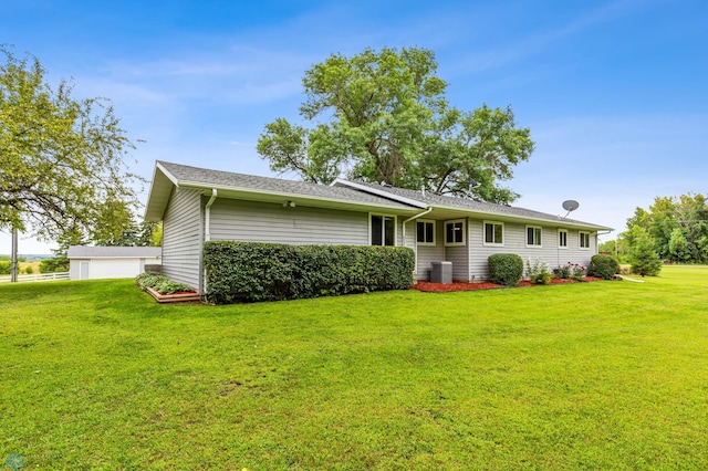 rear view of property featuring a lawn, cooling unit, and a garage