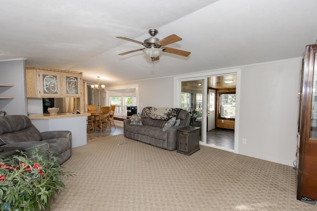 living room with ceiling fan with notable chandelier, crown molding, carpet floors, and vaulted ceiling