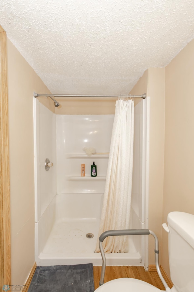 bathroom featuring hardwood / wood-style flooring, a textured ceiling, a shower with shower curtain, and toilet