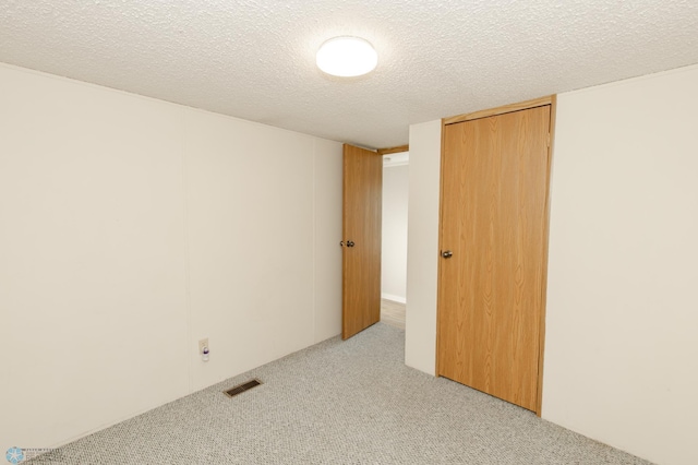 unfurnished bedroom with a textured ceiling, a closet, and light colored carpet