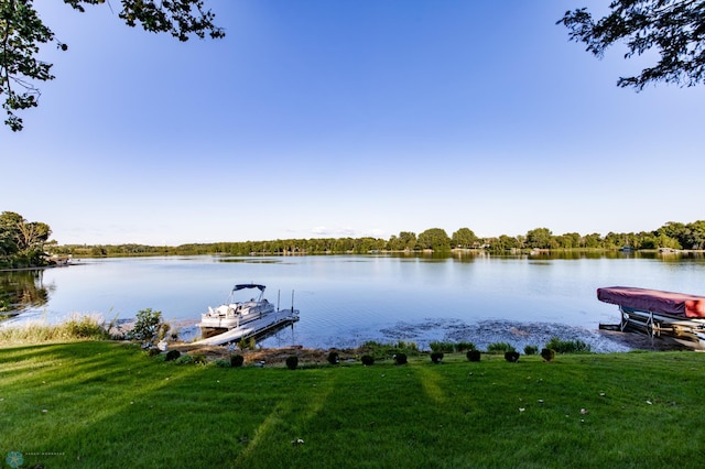 view of dock with a lawn and a water view