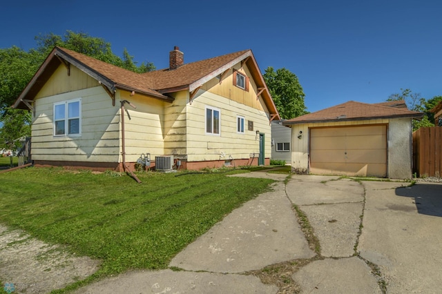 view of front of property with an outbuilding, central AC unit, a front yard, and a garage