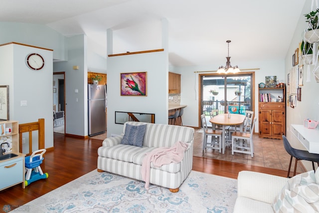 living room featuring dark hardwood / wood-style floors, lofted ceiling, and an inviting chandelier