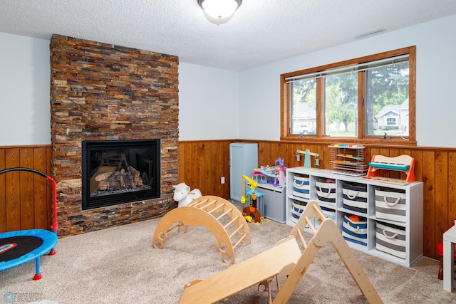 game room with a fireplace, a textured ceiling, and light carpet