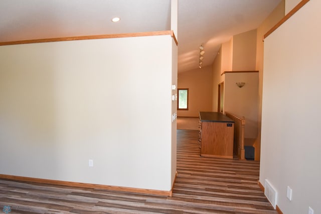 hall with ornamental molding, lofted ceiling, and dark hardwood / wood-style flooring