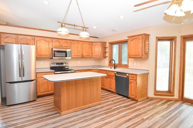 kitchen with ceiling fan, hanging light fixtures, a kitchen island, stainless steel appliances, and light hardwood / wood-style floors