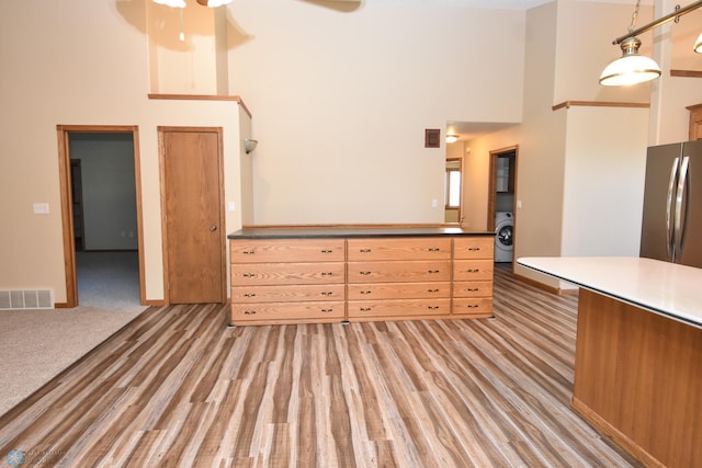 kitchen featuring hanging light fixtures, stainless steel fridge, a towering ceiling, washer / dryer, and ceiling fan