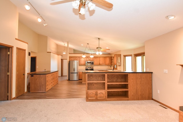 kitchen with appliances with stainless steel finishes, kitchen peninsula, lofted ceiling, ceiling fan, and light carpet