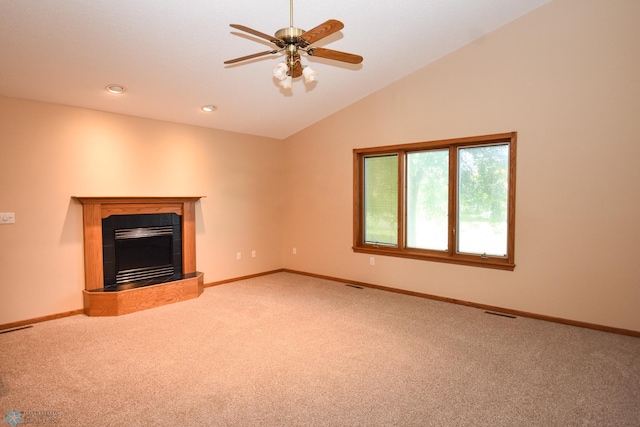 unfurnished living room with a tiled fireplace, ceiling fan, vaulted ceiling, and carpet floors