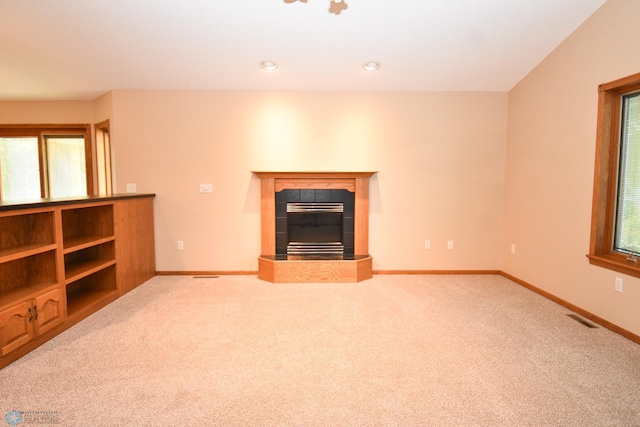 unfurnished living room with light colored carpet and a tile fireplace