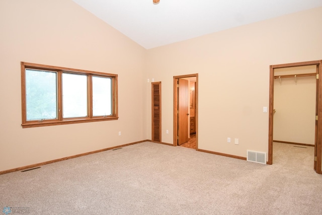 unfurnished bedroom featuring light colored carpet, a closet, vaulted ceiling, and a walk in closet