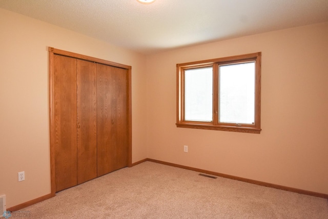 unfurnished bedroom with light carpet and a closet