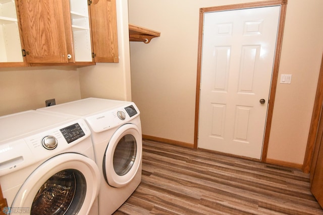 laundry area with cabinets, hardwood / wood-style floors, and washing machine and dryer