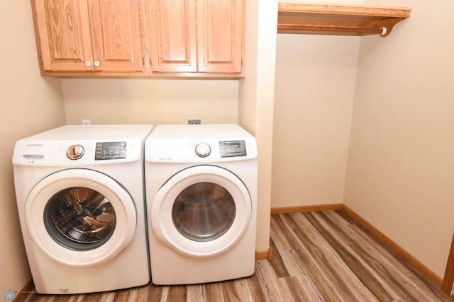 washroom featuring cabinets, hardwood / wood-style flooring, and washer and clothes dryer