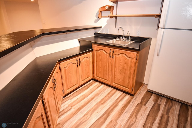 kitchen with light hardwood / wood-style flooring, white fridge, and sink