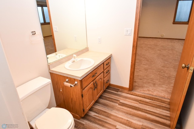 bathroom with wood-type flooring, vanity, and toilet