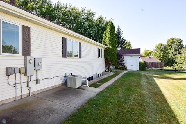 view of side of home featuring a patio, a yard, an outdoor structure, and central AC unit