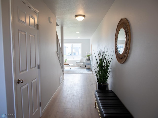 hallway featuring light hardwood / wood-style flooring and a textured ceiling