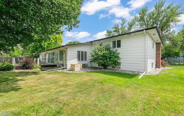 rear view of property featuring central AC unit and a lawn