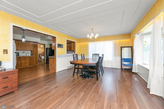 dining room featuring a textured ceiling, plenty of natural light, a notable chandelier, and hardwood / wood-style flooring