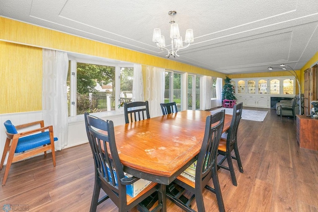 dining area featuring hardwood / wood-style floors, an inviting chandelier, and a textured ceiling