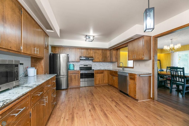 kitchen featuring light wood-type flooring, hanging light fixtures, a chandelier, and stainless steel appliances