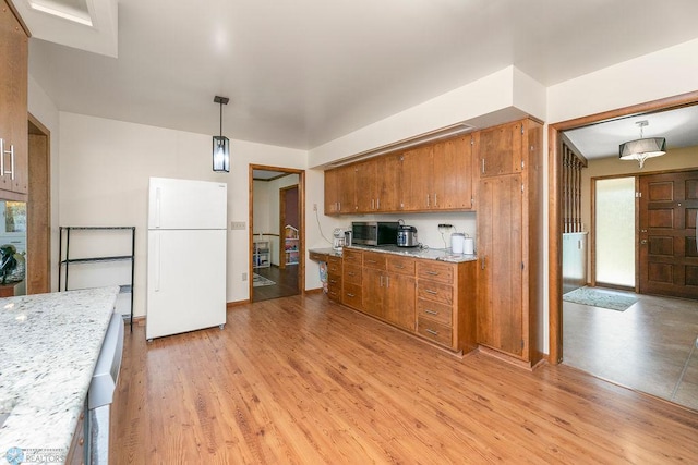 kitchen with light hardwood / wood-style floors, white fridge, and decorative light fixtures