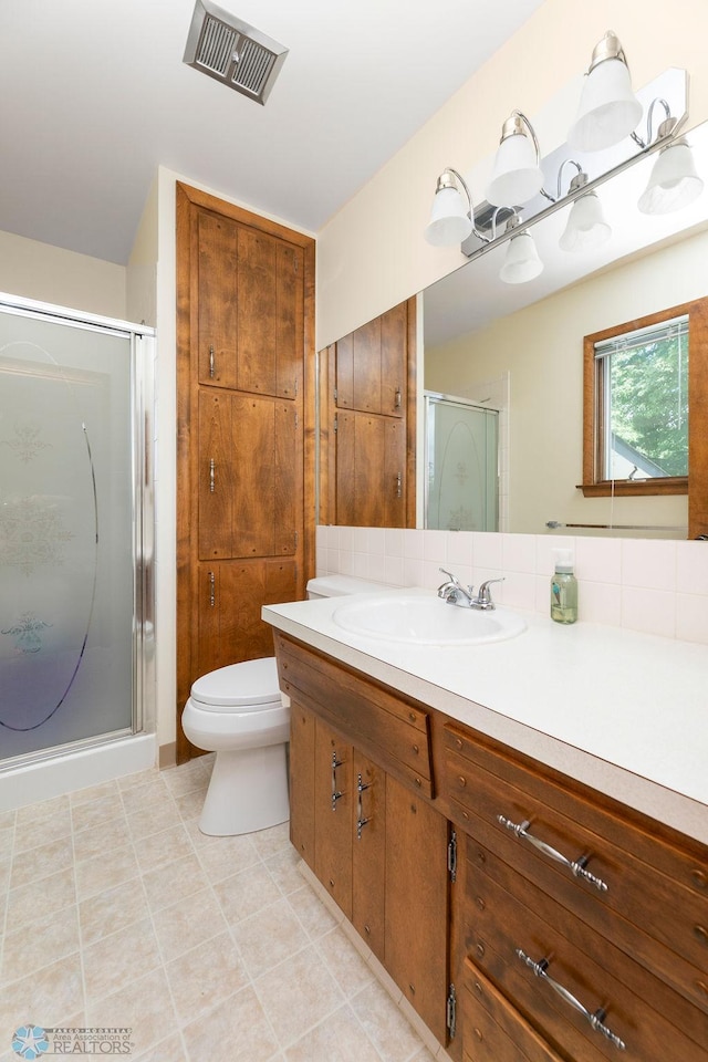 bathroom featuring tile patterned flooring, toilet, walk in shower, and vanity