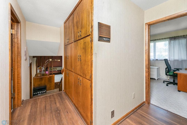 corridor featuring a textured ceiling and carpet flooring