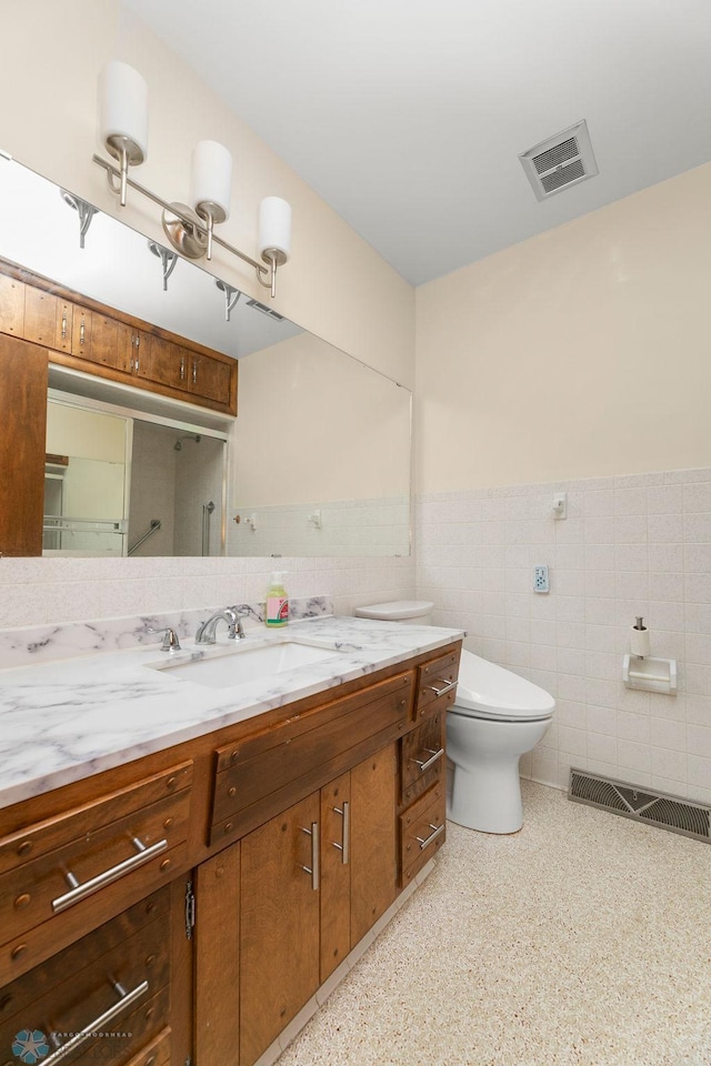 bathroom featuring tile walls, vanity, and toilet