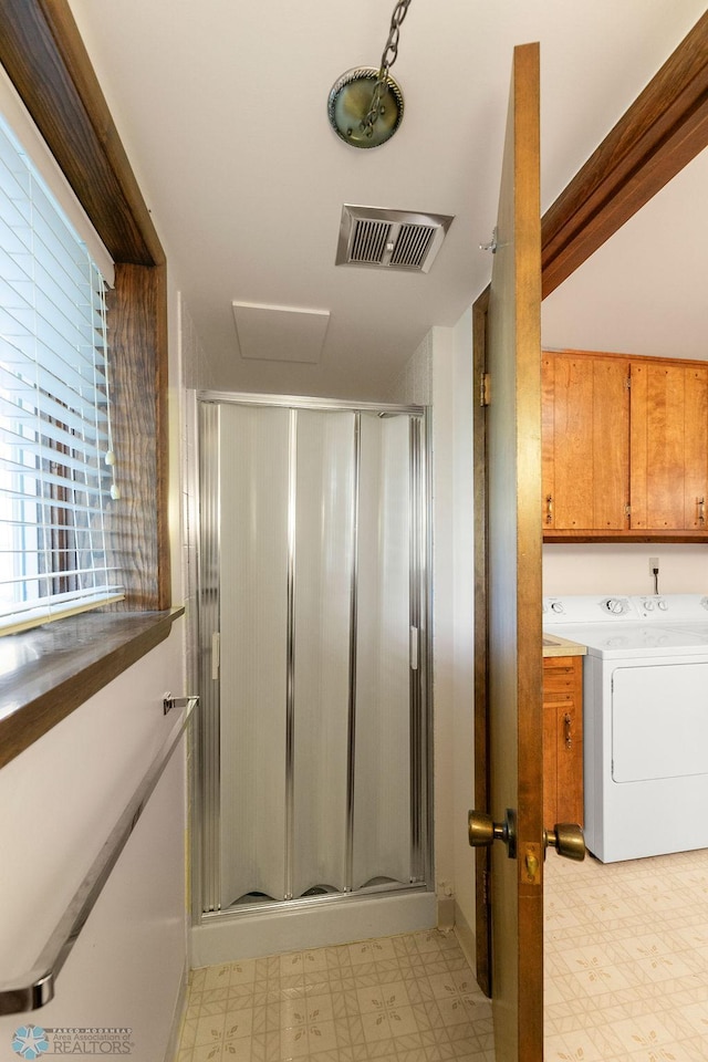 bathroom with washer / clothes dryer, an enclosed shower, and tile patterned flooring