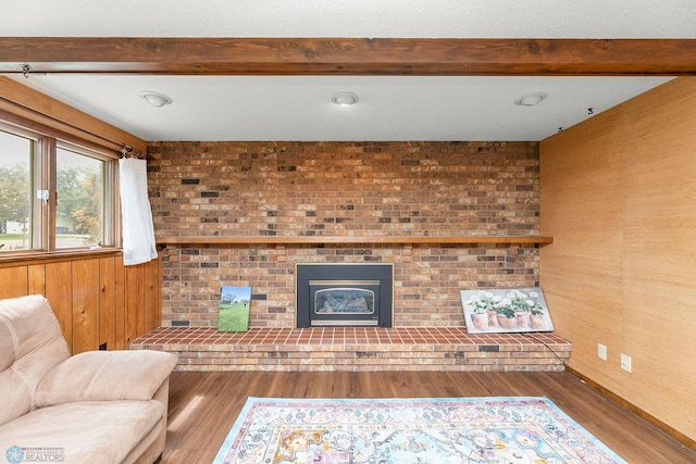 living room featuring hardwood / wood-style flooring, beam ceiling, and a brick fireplace