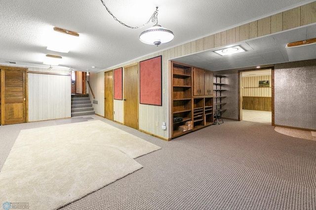 basement with a textured ceiling, wooden walls, and light carpet