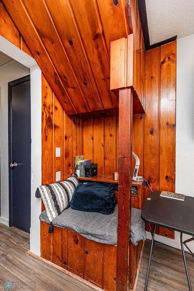 living area with wood walls, a textured ceiling, hardwood / wood-style floors, and lofted ceiling