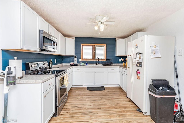 kitchen with ceiling fan, light wood-type flooring, stainless steel appliances, and white cabinets