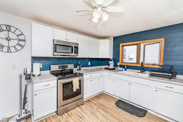 kitchen with light hardwood / wood-style flooring, white cabinets, and stainless steel appliances