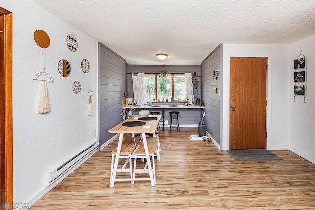 dining space featuring light hardwood / wood-style floors, a textured ceiling, and baseboard heating