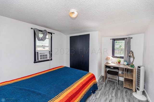 bedroom featuring wood-type flooring, a textured ceiling, and cooling unit