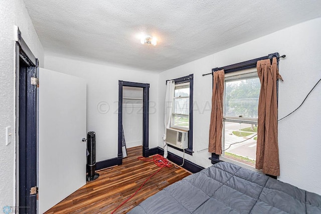 bedroom with dark wood-type flooring, a textured ceiling, and multiple windows