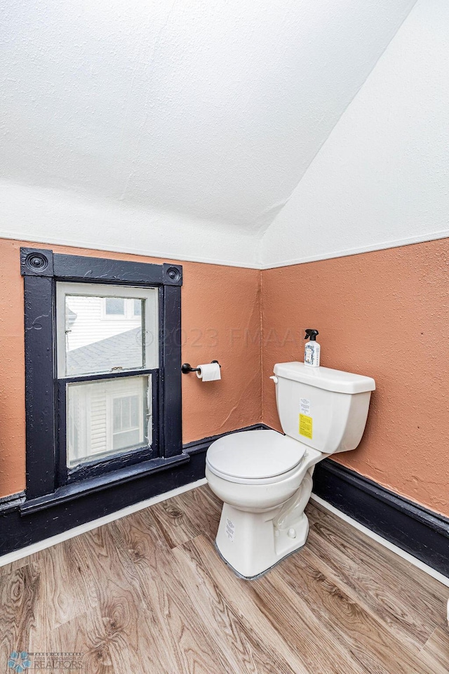 bathroom featuring lofted ceiling, wood-type flooring, a textured ceiling, and toilet