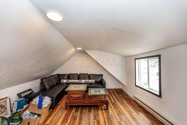 additional living space featuring lofted ceiling, hardwood / wood-style flooring, a textured ceiling, and a baseboard radiator