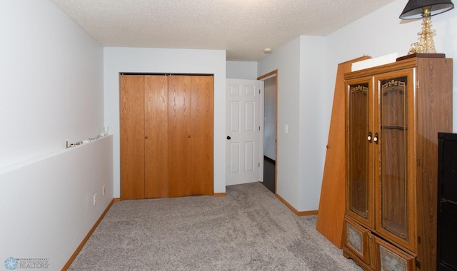 unfurnished bedroom featuring a textured ceiling, light carpet, and a closet