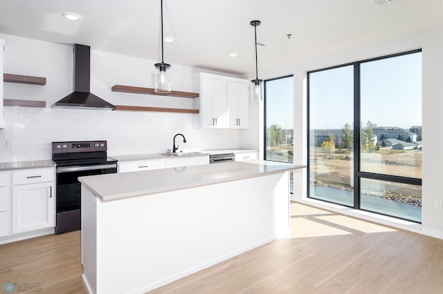 kitchen featuring white cabinetry, electric range oven, wall chimney exhaust hood, pendant lighting, and sink