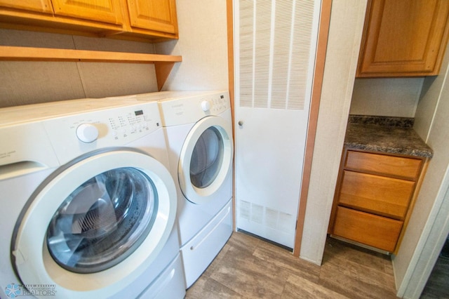 clothes washing area with separate washer and dryer, light hardwood / wood-style floors, and cabinets