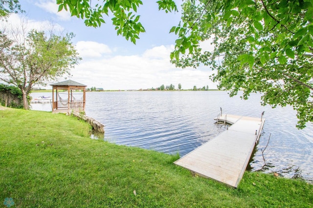 dock area with a gazebo, a water view, and a yard