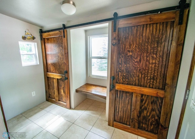 interior space featuring light tile patterned flooring and a barn door