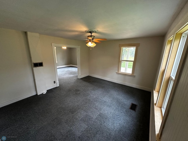 spare room featuring dark colored carpet and ceiling fan