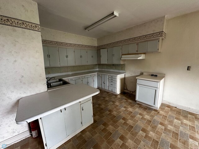 kitchen featuring sink, a breakfast bar, kitchen peninsula, and dark tile patterned floors