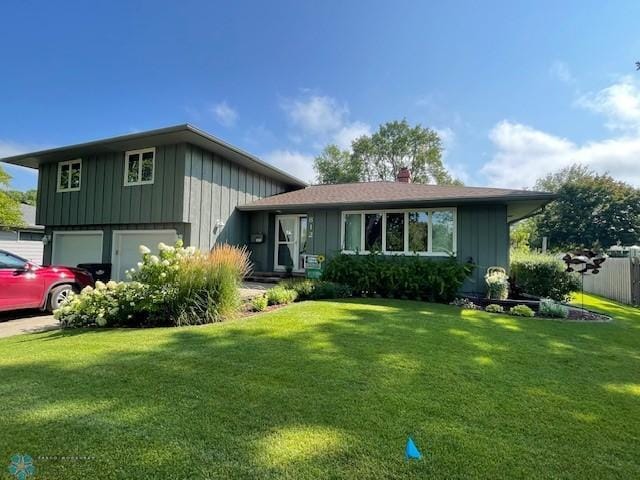 tri-level home featuring a garage and a front lawn