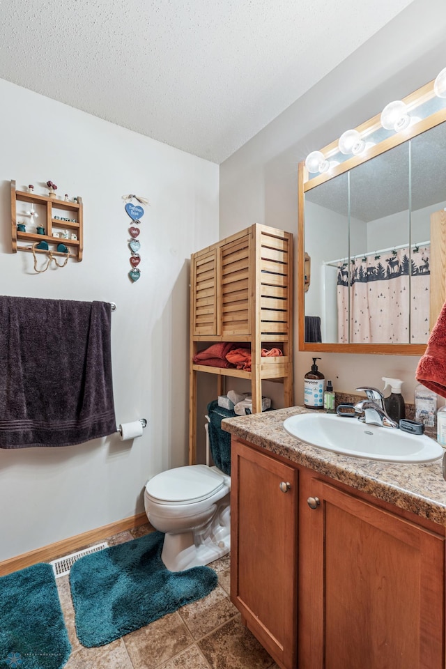 bathroom with tile patterned floors, a textured ceiling, vanity, and toilet